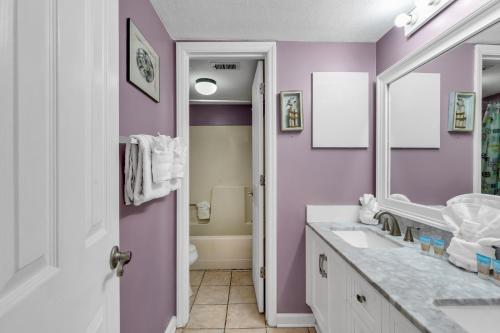 a purple bathroom with a sink and a mirror at Spectacular Oceanview Condos in Myrtle Beach