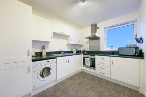 a kitchen with white cabinets and a washer and dryer at Castle Terrace - Grampian Lettings Ltd in Aberdeen