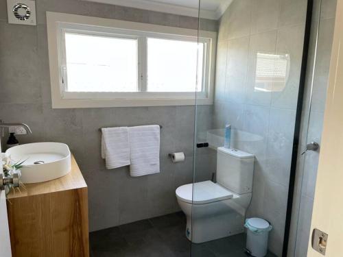 a bathroom with a toilet and a sink and a window at Noahs Beach House - at Flynns in Port Macquarie