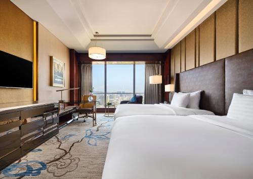 a hotel room with two beds and a flat screen tv at Sanding New Century Grand Hotel Yiwu in Yiwu