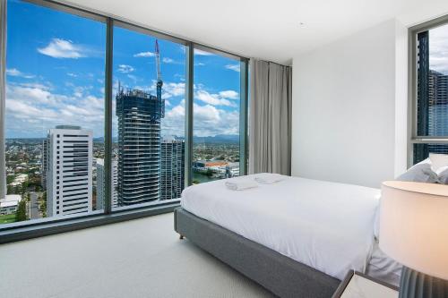 a bedroom with a white bed and large windows at Signature Broadbeach Ocean Views Apartment - CoastHM in Gold Coast