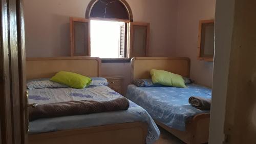 sypialnia z 2 łóżkami i oknem w obiekcie بيت سيدون السياحي w mieście Aswan