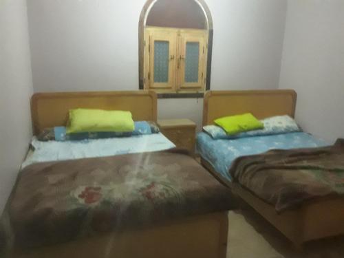 2 łóżka w pokoju z lustrem w obiekcie بيت سيدون السياحي w mieście Aswan