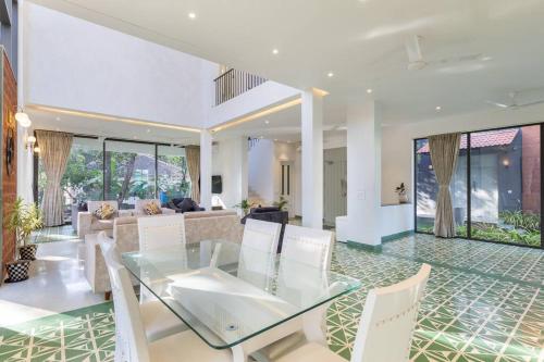 a dining room with a glass table and white chairs at 3BHK Villa with Private Pool near Anjuna in Old Goa