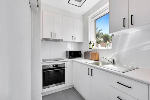 a kitchen with white cabinets and a sink and a window at Acacia South Yarra - Free parking and Wi-Fi in Melbourne