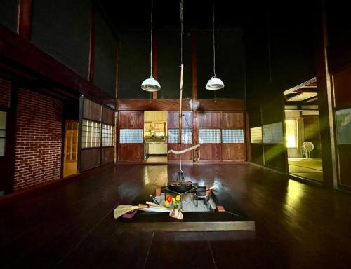 a room with a wooden floor with a stove and lights at 佐渡島に残る築130年の伝統的な古民家｜東夢 in Sado