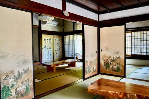 a room with paintings on the walls and a table at 佐渡島に残る築130年の伝統的な古民家｜東夢 in Sado