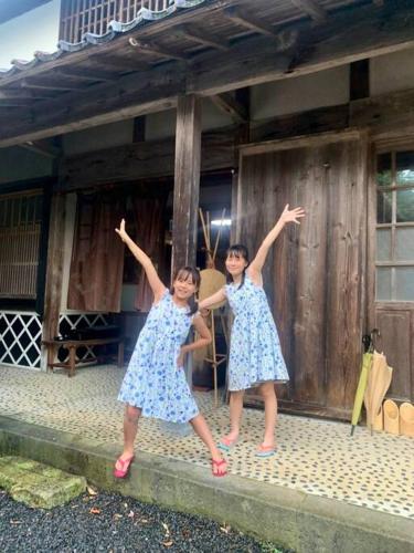two young girls are standing in front of a building at 佐渡島に残る築130年の伝統的な古民家｜東夢 in Sado