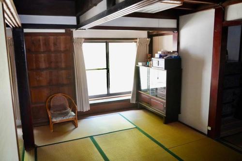 a room with a chair and a large window at 佐渡島に残る築130年の伝統的な古民家｜東夢 in Sado