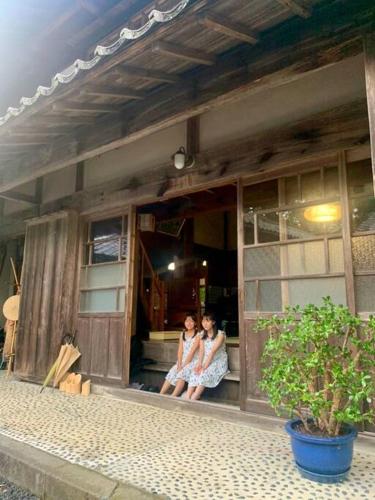 two women sitting on the porch of a building at 佐渡島に残る築130年の伝統的な古民家｜東夢 in Sado