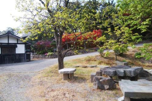 a park with benches and a tree and a road at 佐渡島に残る築130年の伝統的な古民家｜東夢 in Sado
