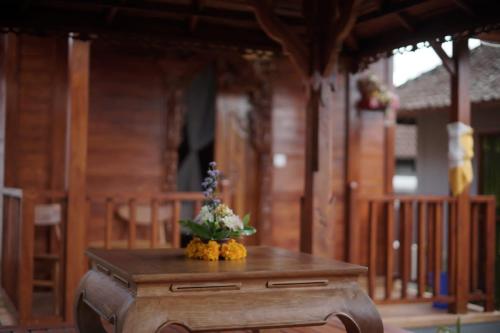 una mesa de madera con un arreglo floral encima en Teba Junjungan Cottages en Ubud