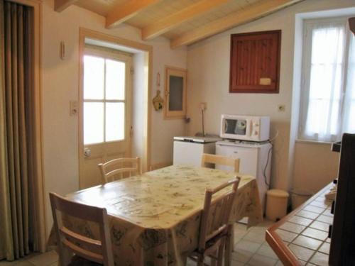 une cuisine avec une table avec des chaises et un micro-ondes dans l'établissement Maison simple à 200m des commerces, proche plage, 3 couchages - Noirmoutier-en-l'Île - FR-1-224B-620, à Noirmoutier-en-l'lle