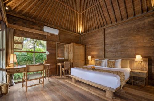 a bedroom with a bed and a desk at RUMAH KAYU RESORT in Ubud