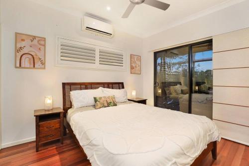 a bedroom with a large white bed and a window at Luxury Holiday Home in Alex - Heated Pool - Pets Allowed in Alexandra Headland