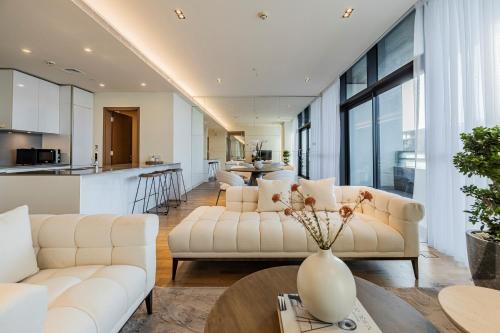 een woonkamer met 2 witte banken en een keuken bij 1 Bed Community View 5th Fl City Walk B7 in Dubai