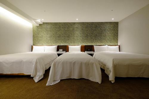 Zimmer mit 3 Betten und weißer Bettwäsche in der Unterkunft Hotel Puri Taipei Station Branch in Taipeh