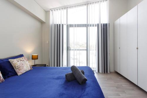 1 dormitorio con cama azul y ventana grande en Waverley apartment F-two bedrooms wifi available, en Perth