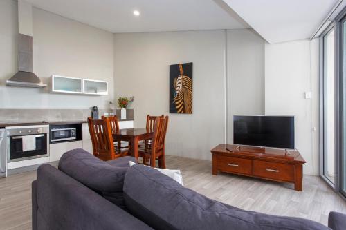 a living room with a couch and a tv and a table at Waverley apartment B-one bedroom wifi available in Perth