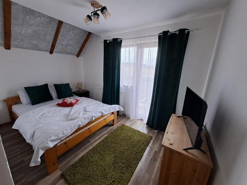 a bedroom with a bed and a flat screen tv at Vis Împlinit in Cîrţişoara
