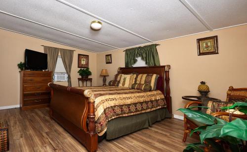 a bedroom with a bed and a dresser and a television at Pleasant Days Lodging Tropical Master Suite in Homosassa