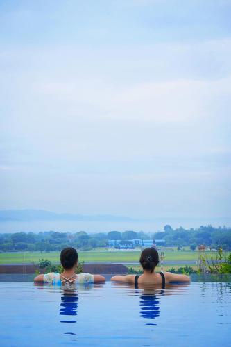 two women sitting in the water in a pool at Platinum Adisucipto Hotel & Conference Center in Yogyakarta