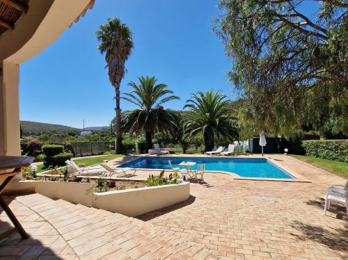 a swimming pool in a yard with palm trees at Casa da Aldeia in Bensafrim
