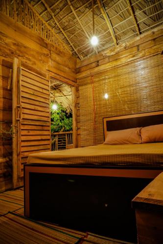 a bedroom with a bed in a wooden room at Eco Bliss Cottages - Thanamalwila in Nikawewa