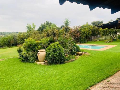 a yard with a swimming pool and green grass at The Manor in Midrand