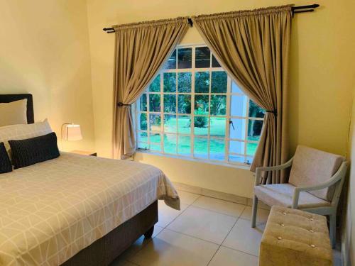a bedroom with a bed and a window and a chair at The Manor in Midrand