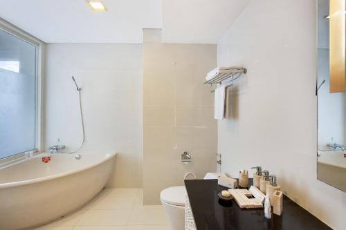 a bathroom with a tub and a toilet and a sink at Jambuluwuk Malioboro Hotel Yogyakarta in Yogyakarta