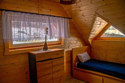 a room with a bed and a window in a log cabin at Domek Muflon w Górach Sowich in Jugów