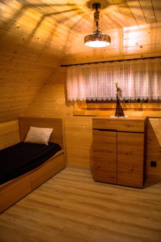 a bedroom in a log cabin with a bed and a window at Domek Muflon w Górach Sowich in Jugów