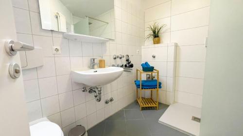 La salle de bains blanche est pourvue d'un lavabo et d'un miroir. dans l'établissement Strandhaus-Nordseebrandung-Fewo-C1-4, à Cuxhaven