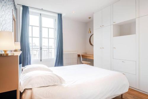 een witte slaapkamer met een bed en een bureau bij Le Jacaranda-à 2 min de la plage, Hyper Centre de Dinard, vue mer de la fenêtre in Dinard