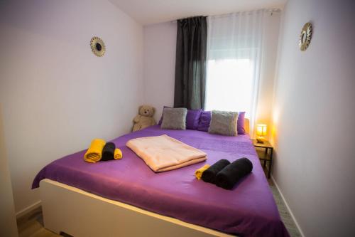 a small bedroom with a purple bed with a window at Apartmani Remete in Zagreb