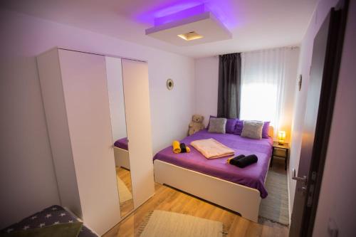 ein kleines Schlafzimmer mit einem lila Bett und einem Spiegel in der Unterkunft Apartmani Remete in Zagreb