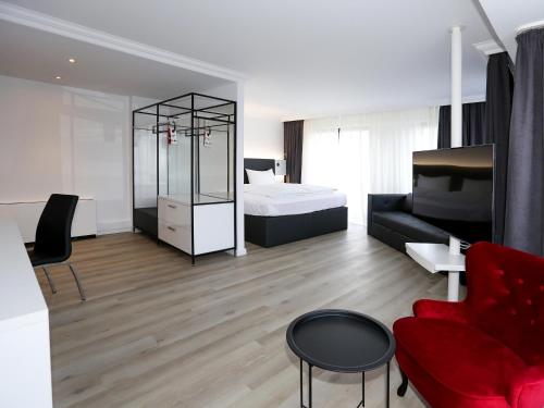 ein Wohnzimmer mit einem Bett und einem roten Sofa in der Unterkunft DORMERO Hotel Meerbusch in Meerbusch