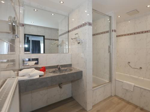 ein Badezimmer mit einem Waschbecken, einer Dusche und einer Badewanne in der Unterkunft DORMERO Hotel Meerbusch in Meerbusch