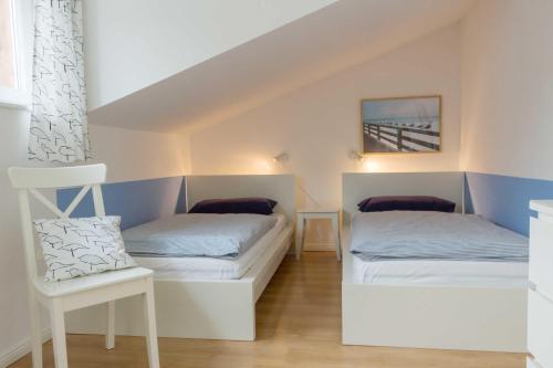 HävenにあるFerienhaus W. Eßigのベッド2台と椅子が備わる小さな客室です。