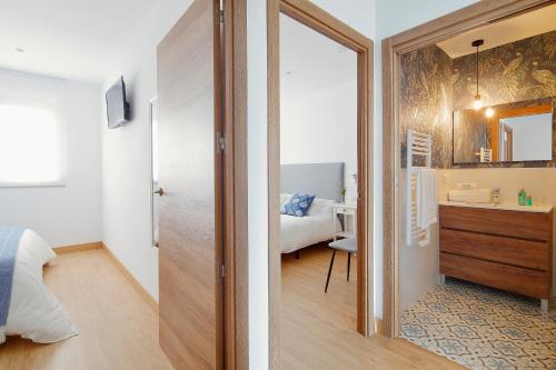 ein Schlafzimmer mit einem Bett und ein Badezimmer mit einem Spiegel in der Unterkunft Balcón de Gijón Apartamentos Boutique in Gijón