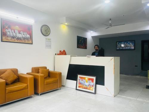 a man standing at a counter in a room with chairs at Hotel Cozy Cave Delhi Aiport in New Delhi