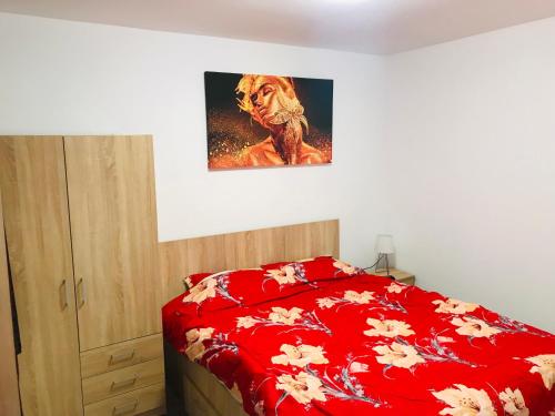a bedroom with a red bed with a painting on the wall at Apartament BD 54 in Roman