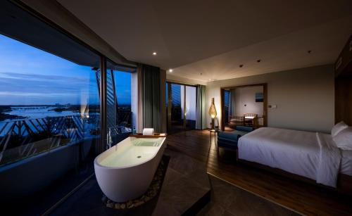 a hotel room with a bath tub and a bed at Bellerive Hoi An Resort and Spa in Hoi An