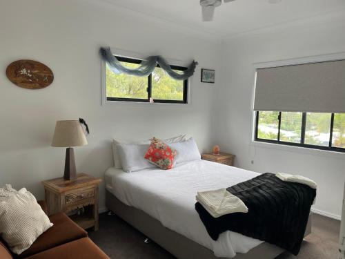 ein Schlafzimmer mit einem Bett und einem Sofa sowie zwei Fenstern in der Unterkunft Himalaya Pet Friendly in Agnes Water