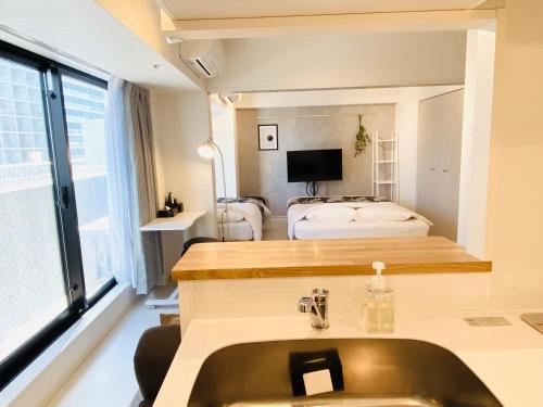 a bathroom with a sink and a bedroom with a bed at FLOWER TERRACE Higashi Shinjuku in Tokyo