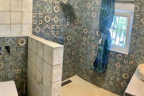 a bathroom with a tiled wall and a window at Superbe villa avec piscine en algarve in Algoz