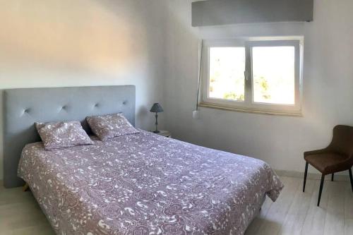 a bedroom with a bed with a purple comforter and a window at Superbe villa avec piscine en algarve in Algoz