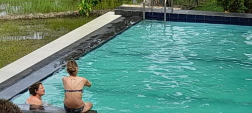 two people are standing in a swimming pool at Traveller's Home Hotel in Tissamaharama