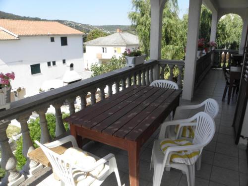 a porch with a wooden table and white chairs at Apartment in Lopar with sea view, terrace, washing machine, dishwasher 593-1 in Lopar